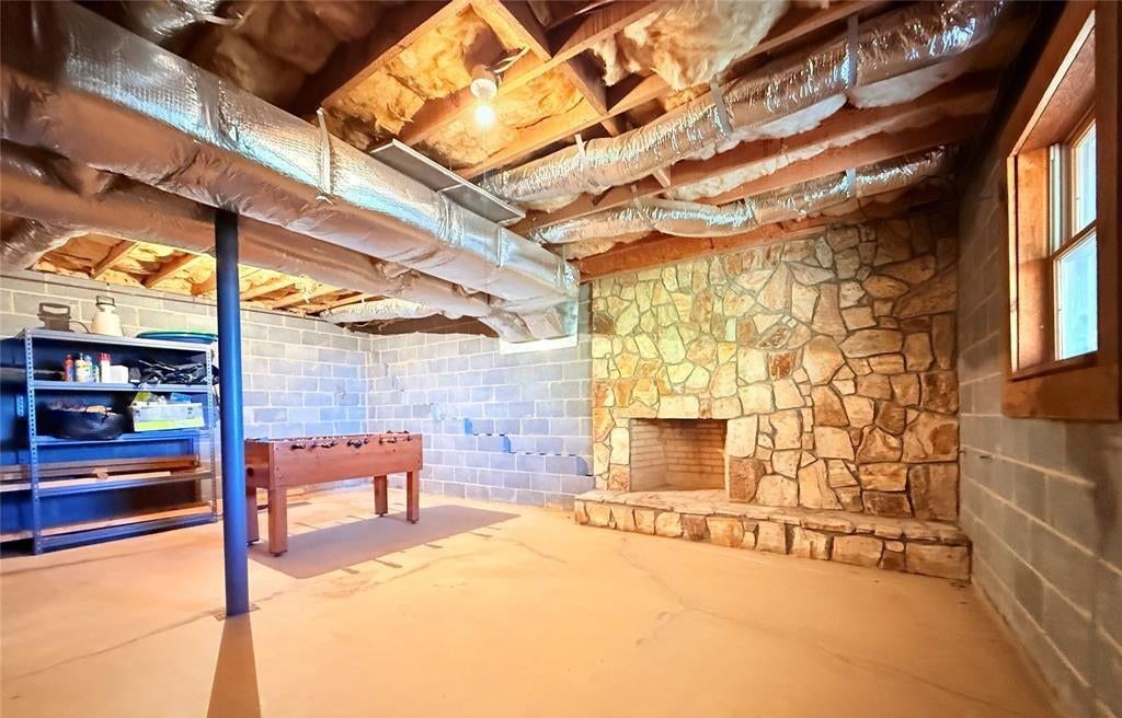 The lower-level game room with a foosball table and a stone fireplace