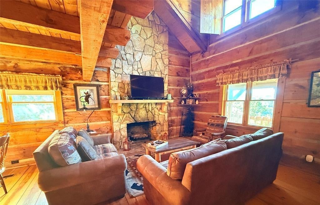 Sofas gathered around the stone fireplace under an open beam ceiling