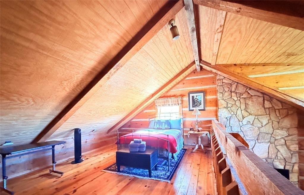 The loft under the A-frame roof with extra beds and a stone chimney wall