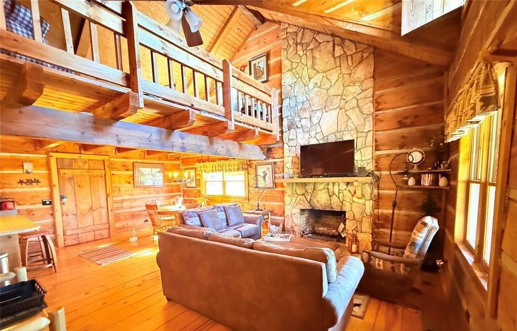 The great room in knotty pine with leather sofas facing the stone fireplace