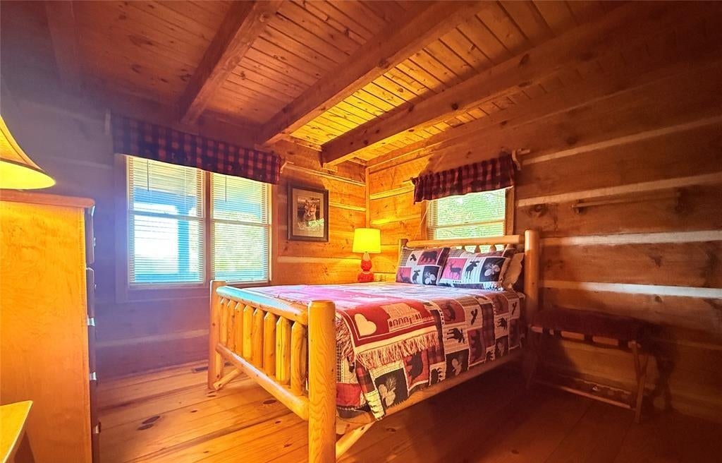 A log-frame bed with a quilt in a pine-panelled bedroom