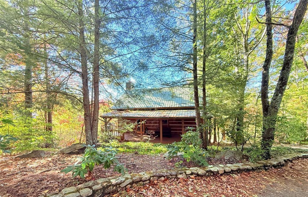 The log cabin seen from the woods below, low and long among the trees